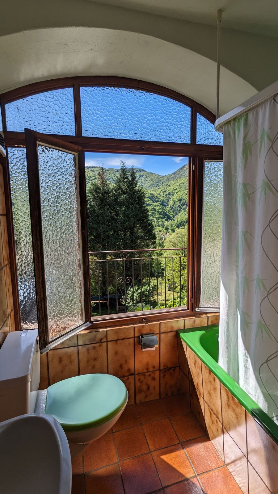 Badezimmer mit Wanne und Fenster ins Grüne